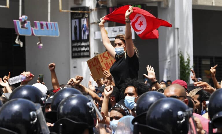 Femme portant un drapeau tunisien, elle-même portée par la foule, durant une manifestation