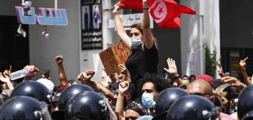 Femme portant un drapeau tunisien, elle-même portée par la foule, durant une manifestation