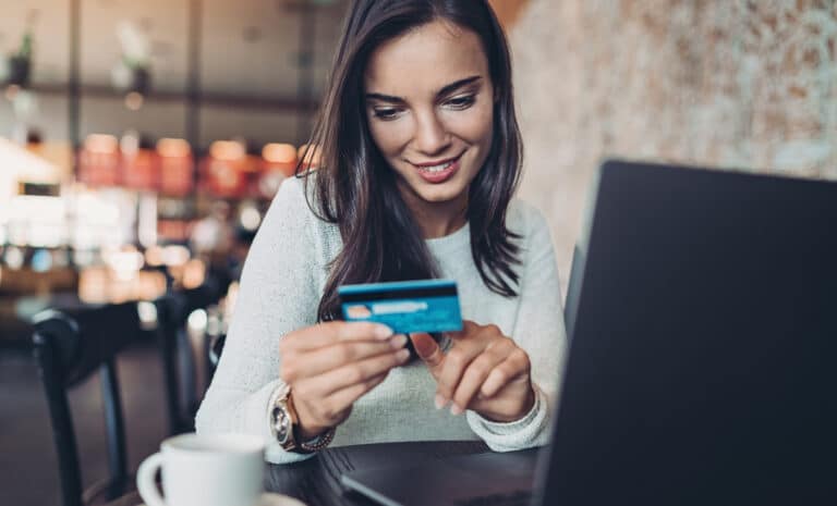 Photo d'une femme tenant une carte de paiement électronique devant un ordinateur portable