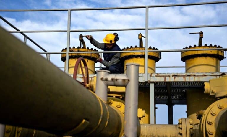 Un travailleur ajuste la tuyauterie d'une station de gaz naturel