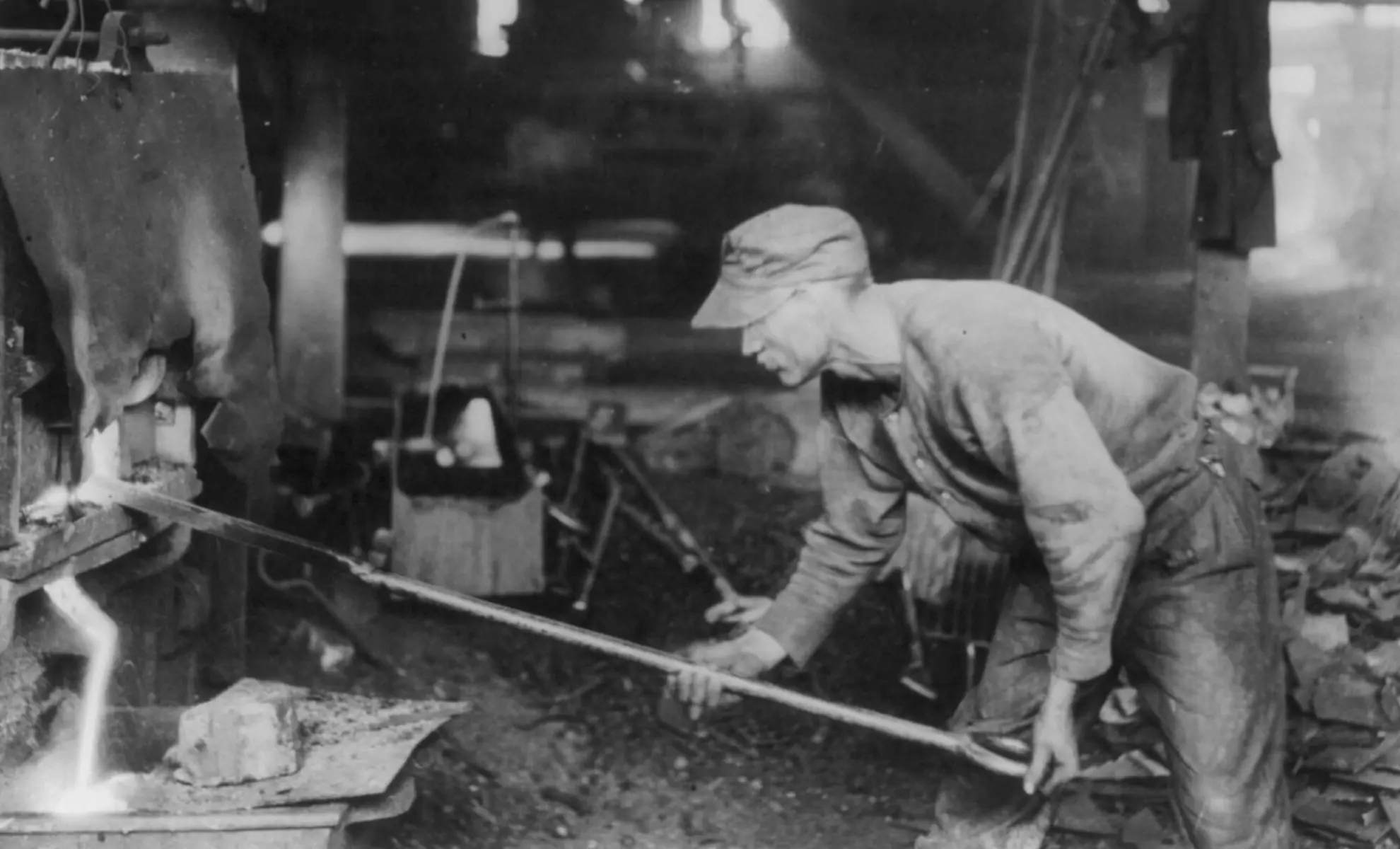 Un puddleur coulant le laitier hors du four de puddlage après avoir extrait les boules de fer (vers 1919)